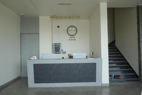 a lobby with a clock on the wall and stairs at Hotel Tavijay in Jhunjhunūn