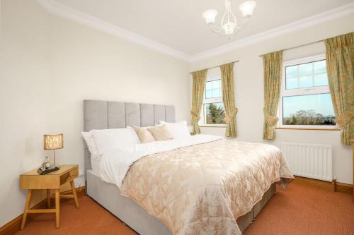 a bedroom with a large bed and two windows at Turner's Corner by Escape Ordinary in Aghadowey