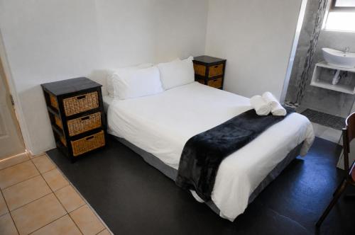a bedroom with a white bed and a sink at Blouberg Beach Retreat in Bloubergstrand