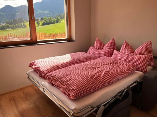 a bed with red and white blankets and a window at Haus Casimir in Reith im Alpbachtal