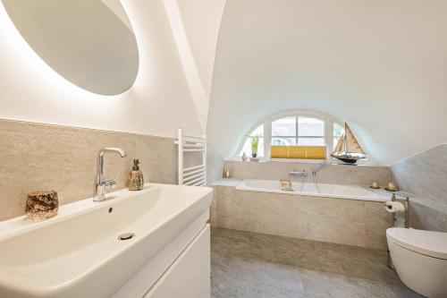 a bathroom with a sink and a tub and a toilet at Fischerdorf Ferienhaus JoHann in Zirchow