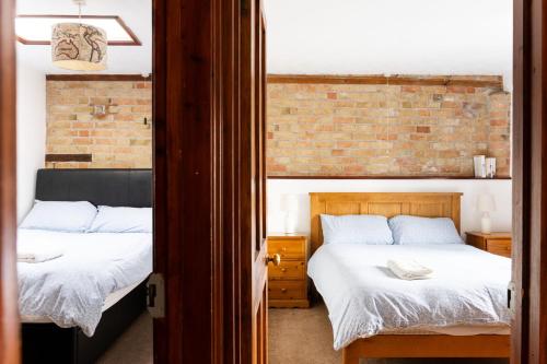 a bedroom with two beds and a brick wall at Cottage 2 at Scald end cottages in Bedford