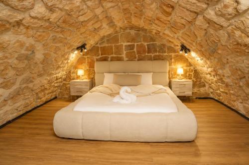 a bedroom with a large bed in a stone wall at האבן והים - סוויטה מדהימה עם ג'קוזי בעיר העתיקה עכו in Acre