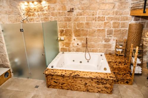 a bathroom with a large tub in a stone wall at האבן והים - סוויטה מדהימה עם ג'קוזי בעיר העתיקה עכו in Acre