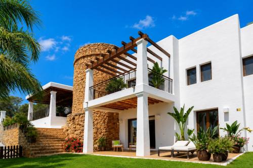 a white house with a balcony and palm trees at New! Villa Llosas de Dalt in Sant Carles de Peralta