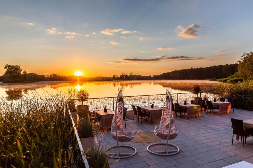 a patio with tables and chairs in front of a lake at Hotel Duo Spa in Janów Lubelski