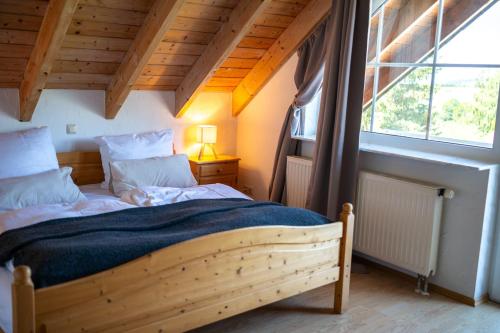 a bedroom with a wooden bed and a large window at Landhaus Schneeberg AusZeit am Küppel & Bright Collection in Gersfeld