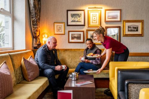 a woman giving a man a plate of food in a restaurant at Patterdale Hotel in Patterdale