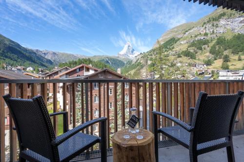 a balcony with two chairs and a table with a view at Hotel Bristol in Zermatt