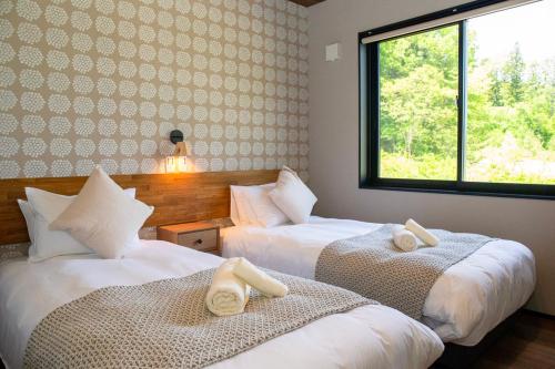 two beds in a room with a window at STARRY The Garden Hakuba Iwatake in Hakuba