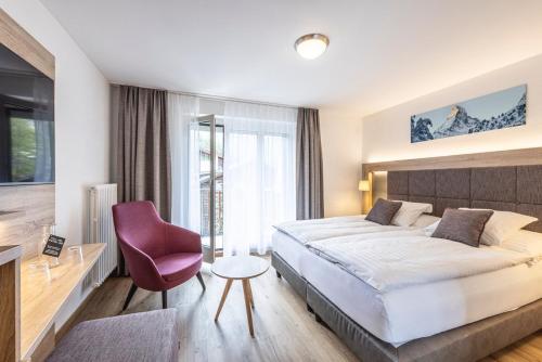 a bedroom with a large bed and a purple chair at Hotel Bristol in Zermatt