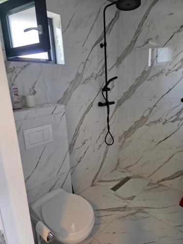 a bathroom with a toilet and a stone wall at Villa Violand 2 in Limanu