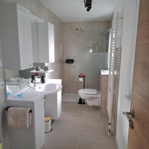 a white bathroom with a sink and a toilet at Eichkobel-Blick in Grünenbach