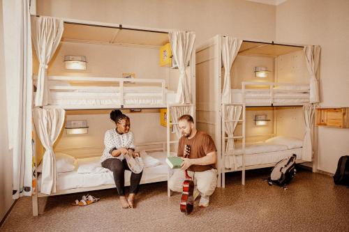 a man and woman sitting in a room with bunk beds at Wombat's City Hostel Budapest in Budapest