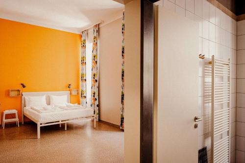 a bedroom with a white bed and a yellow wall at Wombat's City Hostel Budapest in Budapest