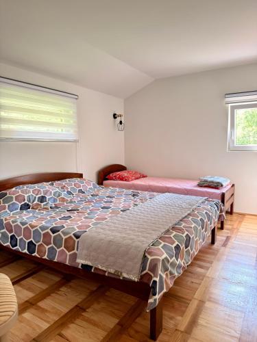 a bedroom with two beds and a window at Kuca za odmor SONATA in Biserske Kuće
