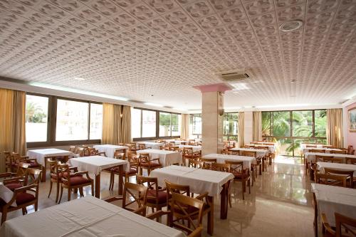 シジョットにあるBJ Bei Juan Hostalの白いテーブルと椅子、窓のあるレストラン