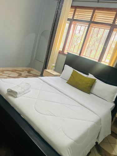 a large white bed in a room with a window at Serenity homes Uganda in Mbale