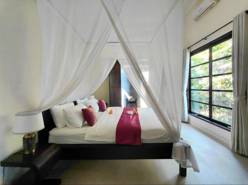 a bedroom with a bed with white sheets and red pillows at Villa Terang Bulan - luxury private beachfront villa in Pengastulan