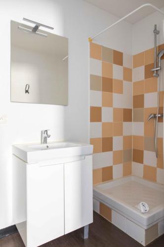 a bathroom with a sink and a tub at Ténéo Apparthotel Bordeaux - Gare Saint Jean in Bordeaux