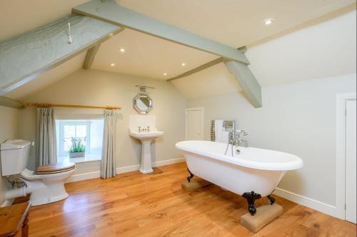 a bathroom with a tub and a toilet and a sink at Hollins Farmhouse in Leyburn