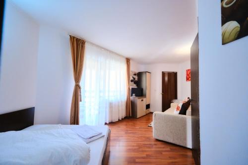 a bedroom with a bed and a couch and a window at Vila Residence in Moieciu de Sus