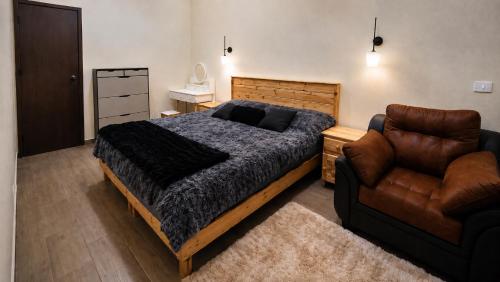 a bedroom with a bed and a leather chair at Casa Amplia con Terraza en Xalapa in Xalapa