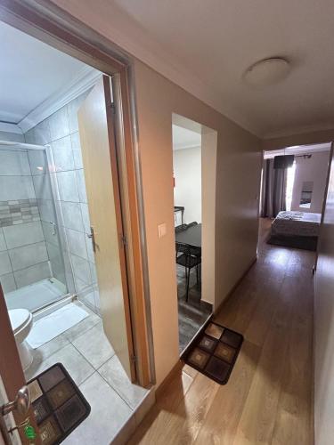a bathroom with a shower and a toilet and a bedroom at Suites & Apartments - DP Setubal in Setúbal