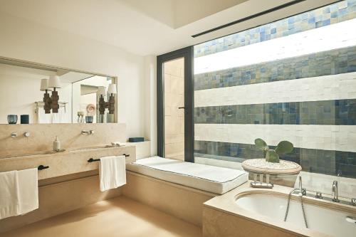 a bathroom with a tub and a sink and a window at Verdura Resort in Ribera