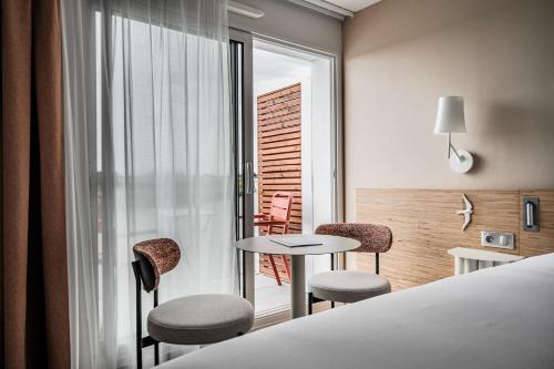 a hotel room with a bed and a table and chairs at Thalazur Carnac in Carnac