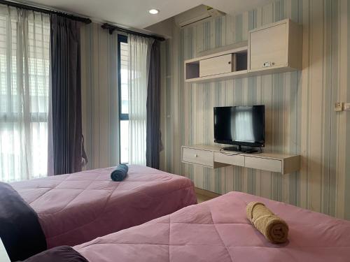 a hotel room with two beds and a television at New Abani in Jomtien Beach