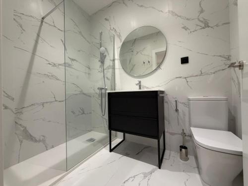 a white bathroom with a sink and a mirror at MTM Rooms in Santander