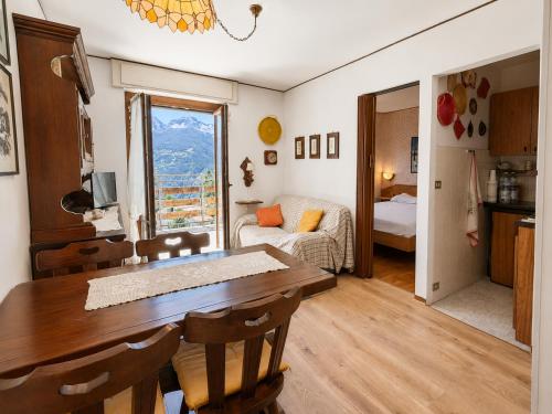 a dining room with a table and a room with a couch at Hostdomus - Villaggio Alpino in Sauze d'Oulx