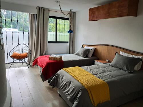 a bedroom with two beds and a chair and a window at Casa Puerto Siete8 in Mexico City