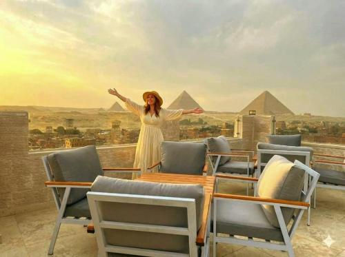 a woman standing on a roof with her arms outstretched at The Nomad Pyramids Boutique Hotel in Cairo