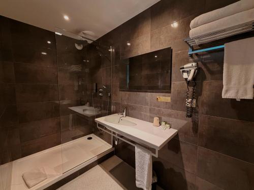 a bathroom with a sink and a shower at Hôtel de La Cloche in Dole