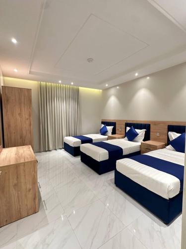 a room with four beds with blue pillows at شقق نطوان المفروشة in Abha