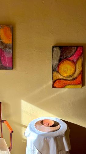 a plate on a table with two paintings on the wall at Casa Manuel in Tinogasta