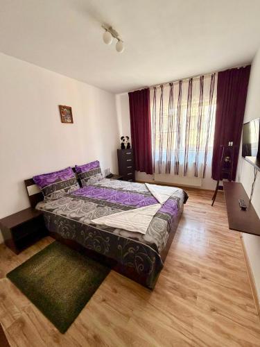 a bedroom with a bed with purple pillows on it at Stejarului Apartment in Floreşti