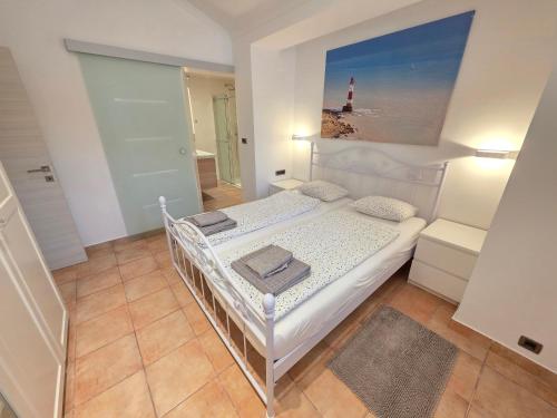 a bedroom with a white bed with a picture of a lighthouse at Villa Dvojac Holiday house with Jacuzzi and grill in Jadranovo