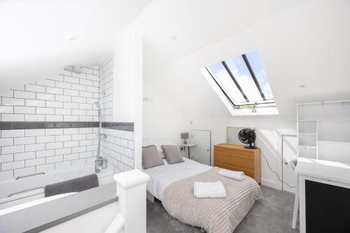 a white bedroom with a bed and a bath tub at Stylish 2BR Cottage in Chesham in Chesham