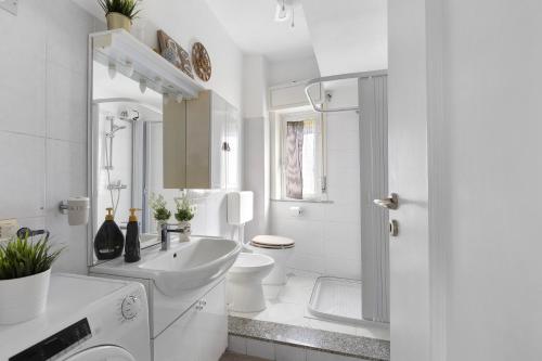 a white bathroom with a sink and a toilet at A due passi dal mare in Oliveri
