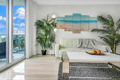 a living room with a white couch and palm trees at Luxury Miami Condos - 1BR-2BR & 3BR in Miami Beach