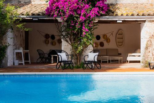 a swimming pool with chairs and flowers next to a house at Can marques in Cunit