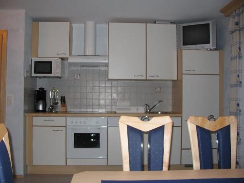 a kitchen with white cabinets and a table and chairs at Gratzerhof in Zederhaus