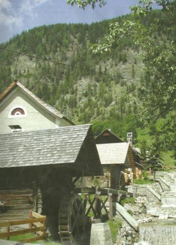 a building with a barn with a mountain in the background at Gratzerhof in Zederhaus