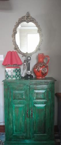 a green cabinet with a mirror and a vase on it at Sailaway in Carbis Bay