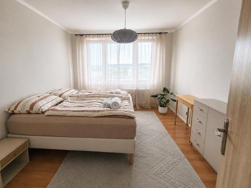 a bedroom with a bed and a desk and a window at Apartmán Malohont in Rimavská Sobota