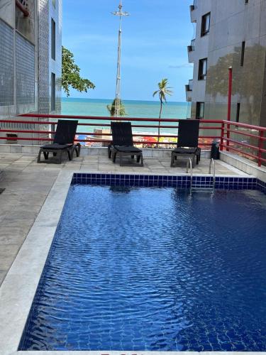 a swimming pool with two chairs and a view of the ocean at MERCURE RECIFE NAVEGANTES · Flat Recife Navegantes - 50 metros da praia. in Recife