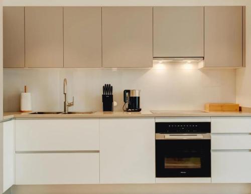 a kitchen with white cabinets and a black oven at Portonovi Marina in Kumbor